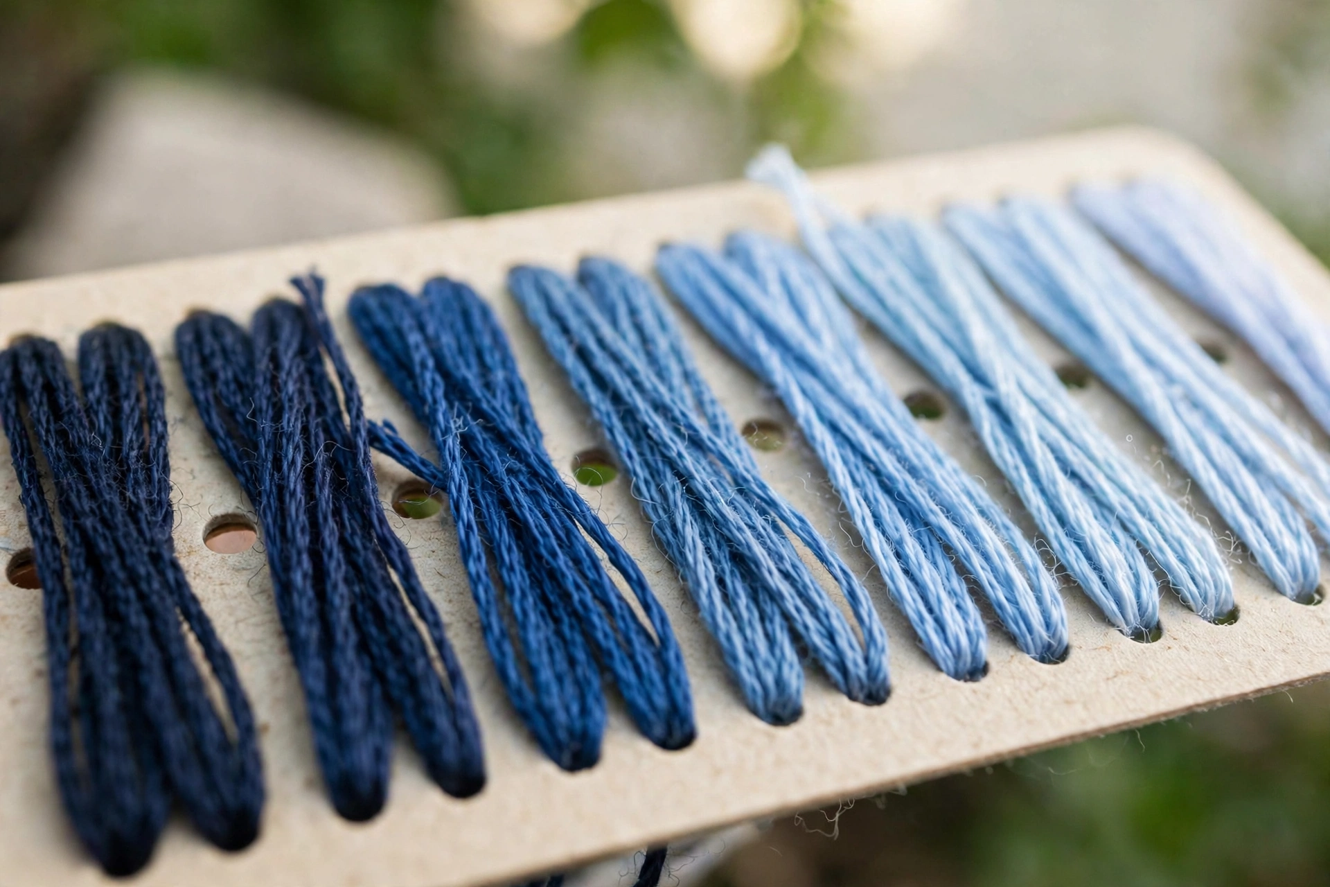 Thread samples on a floss color card showing a blue shade progression from dark to light