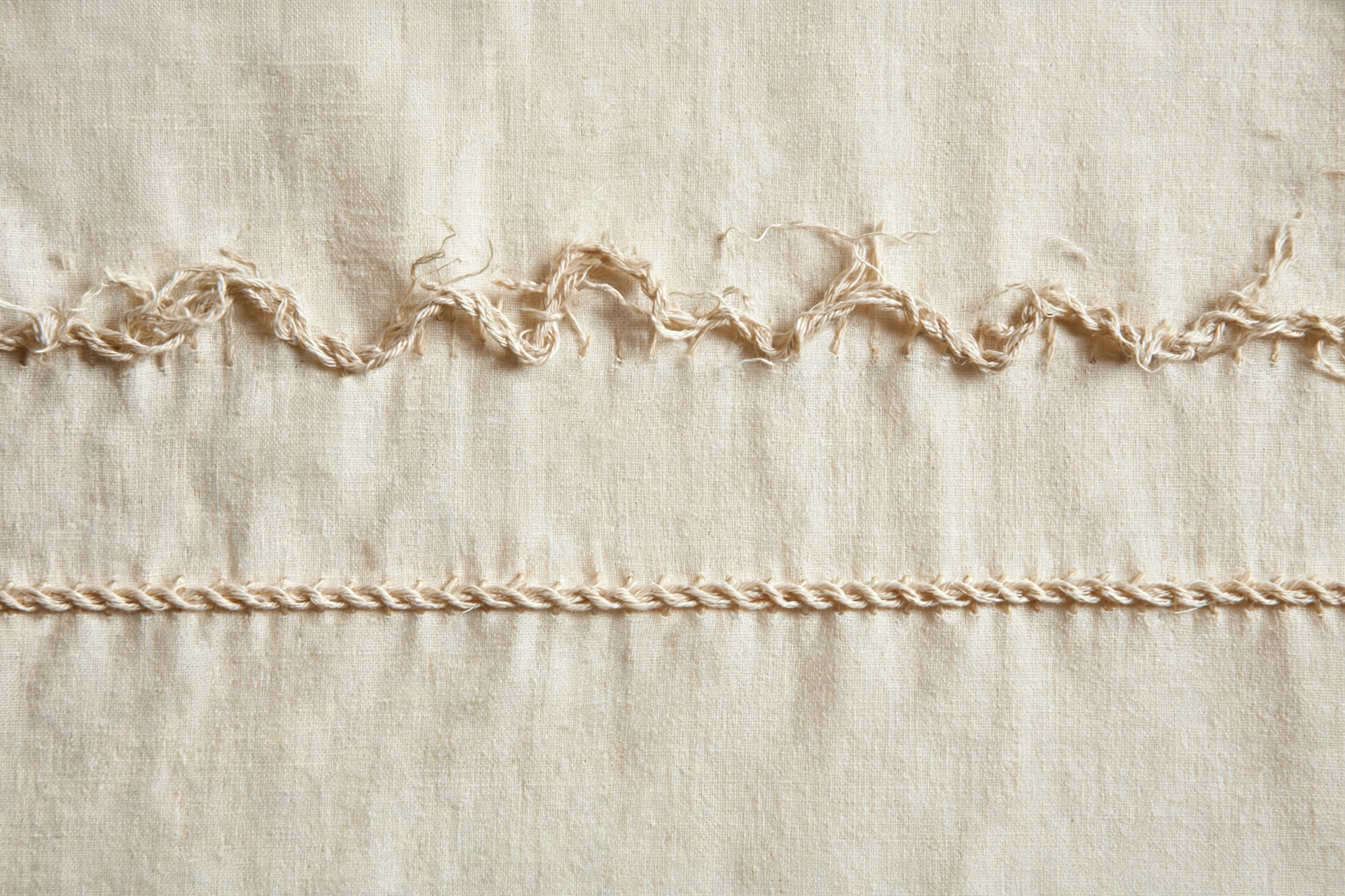 Photorealistic comparison of a wobbly uneven chain stitch row next to a perfectly straight one on cream fabric, instructional detail, natural daylight, landscape orientation, no text